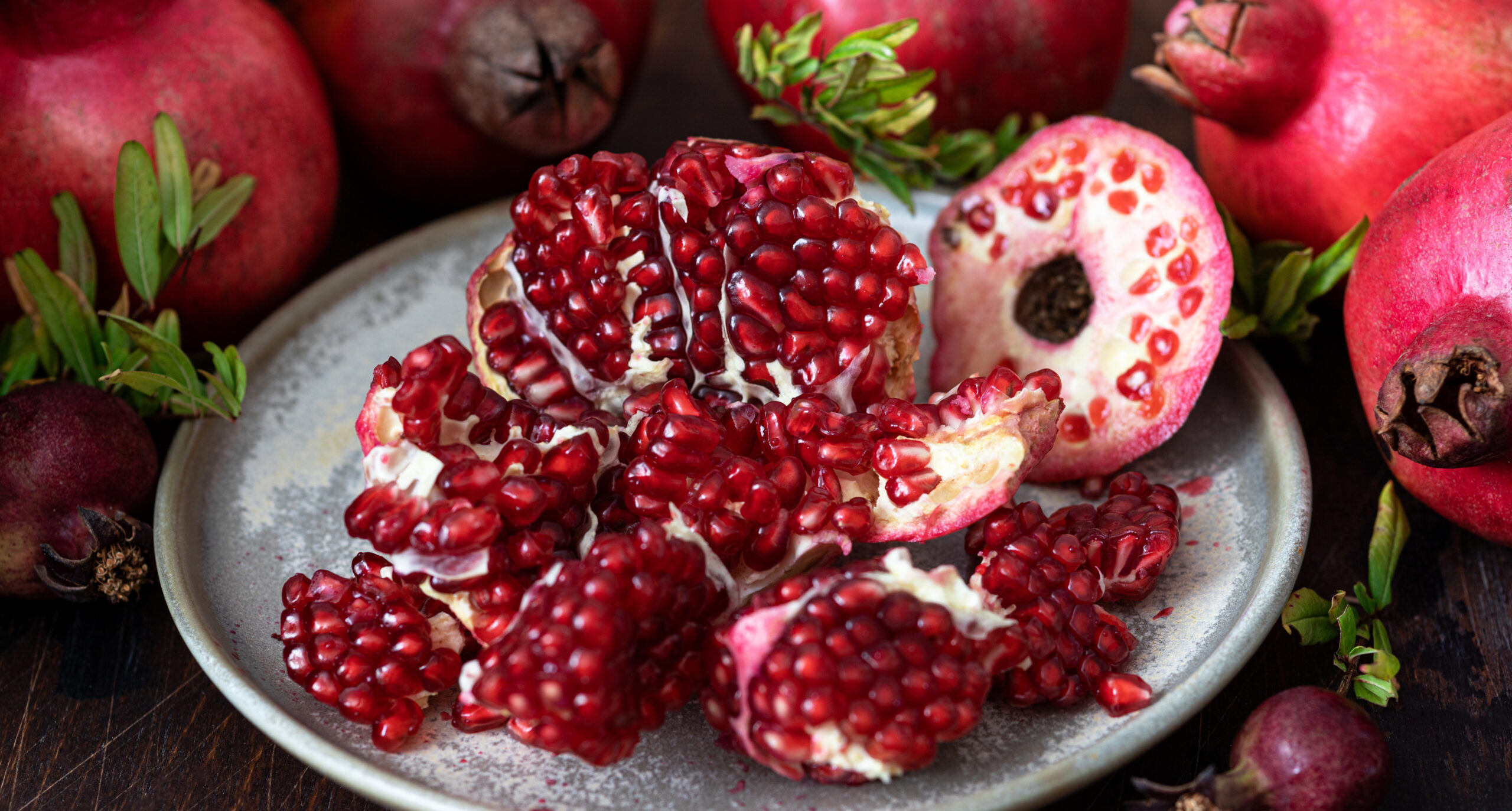 Fresh juicy pomegranate - whole and cut, with leaves on  table
